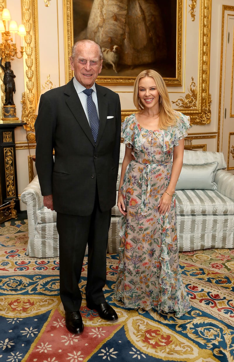 Prince Philip, Duke of Edinburgh, presents Kylie Minogue, in a floral chiffon maxi, with the Britain-Australia Society Award at Windsor Castle on April 4, 2017 in London, England.