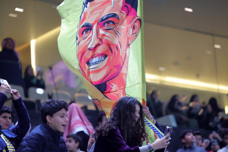 A football fan poses for a "selfie" picture with a flag depicting Al Nassr's Portuguese forward Cristiano Ronaldo. AFP