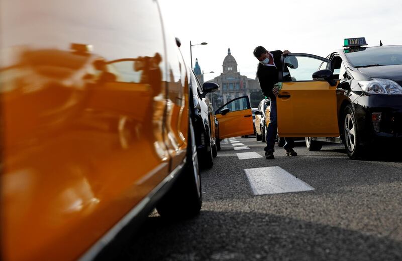 A man cleans a car door as taxi drivers protest against falling demand as a result of new restrictions imposed in Barcelona, Spain. Reuters