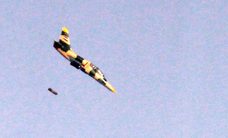 A picture taken on July 25, 2018 from the Tal Saki hill in the Israeli-annexed Golan Heights shows a Syrian Aero L-39 Albatros war plane dropping a payload above buildings across the border in Syria during air strikes backing a Syrian-government-led offensive in the southern province of Quneitra. (Photo by JALAA MAREY / AFP)