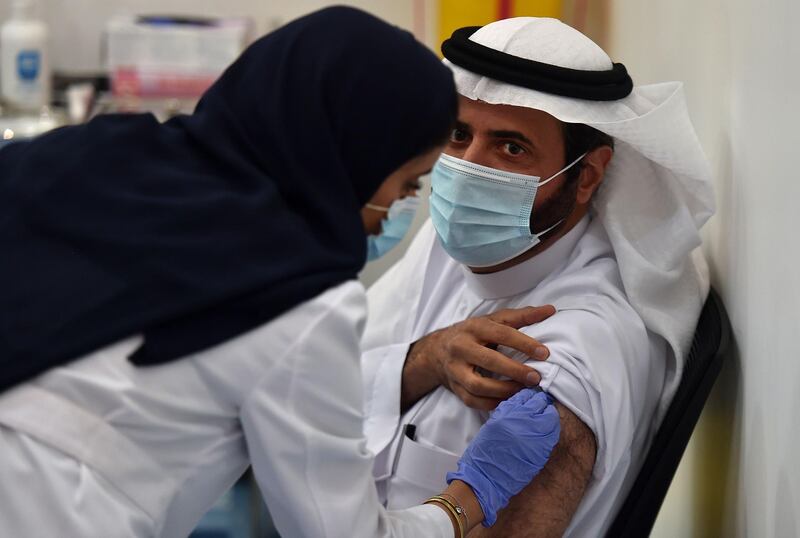 This picture taken on December 17, 2020 shows Saudi Arabia's Health Minister Tawfiq al-Rabiah receiving the Pfizer-BioNTech COVID-19 coronavirus vaccine (Tozinameran) in the capital Riyadh, as part of a vaccination campaign by the Saudi health ministry.  / AFP / FAYEZ NURELDINE
