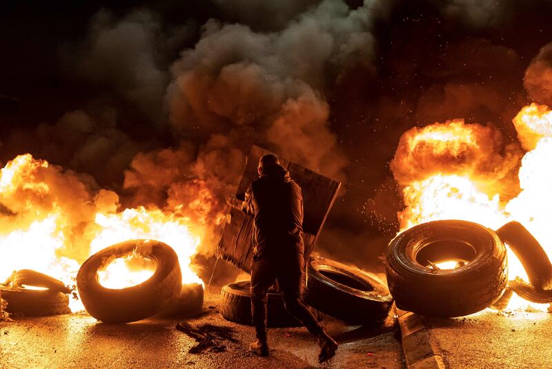 A protester walks near burning tyres in the occupied West Bank. AFP