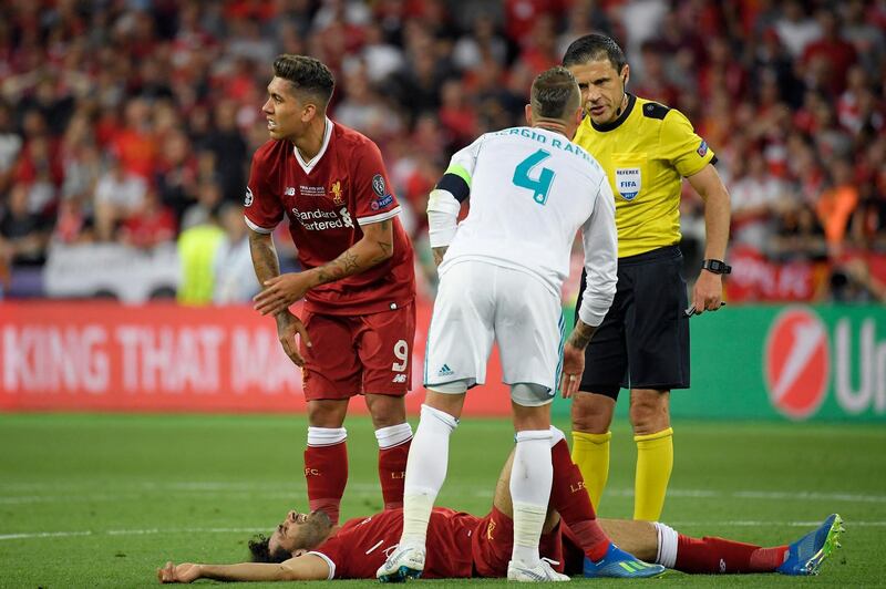 Liverpool's Egyptian forward Mohamed Salah (down) gestures in pain next to Real Madrid's Spanish defender Sergio Ramos (2R), Serbian referee Milorad Mazic (R) and Liverpool's Brazilian forward Roberto Firmino during the UEFA Champions League final football match between Liverpool and Real Madrid at the Olympic Stadium in Kiev, Ukraine on May 26, 2018. (Photo by LLUIS GENE / AFP)