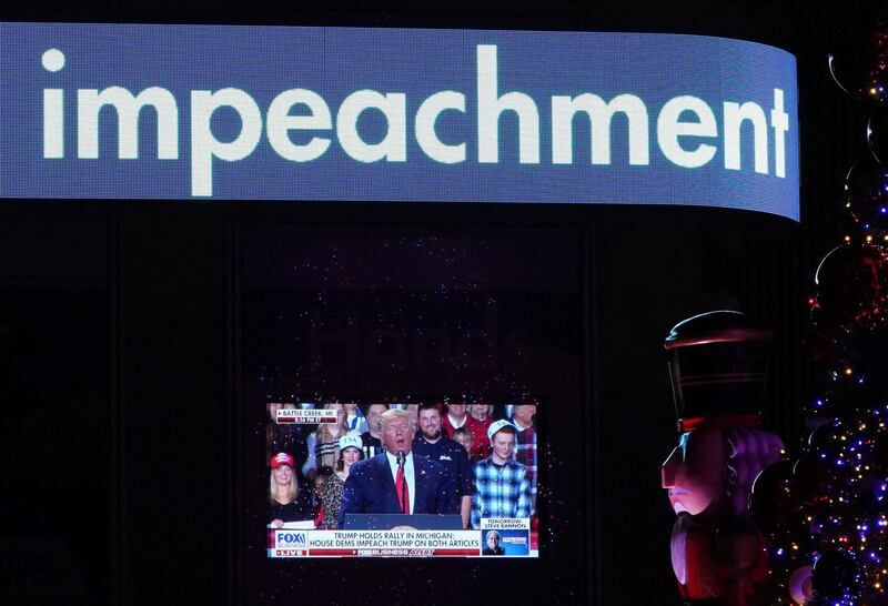 US President Donald Trump is shown on a screen speaking from a rally in Michigan as the the Fox News Headquarters ticker flashes the news of his impeachment for abuse of power in New York on December 18, 2019. - US President Donald Trump was impeached for abuse of power in a historic vote in the House of Representatives on December 18, 2019, setting up a Senate trial on removing him from office after three turbulent years. (Photo by TIMOTHY A. CLARY / AFP)