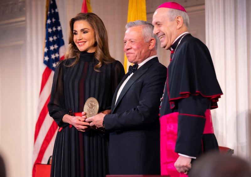 Queen Rania, in a pleated black chiffon dress with a red waist belt, receives the Path to Peace Award in New York along with her husband, on May 9, 2022. AFP