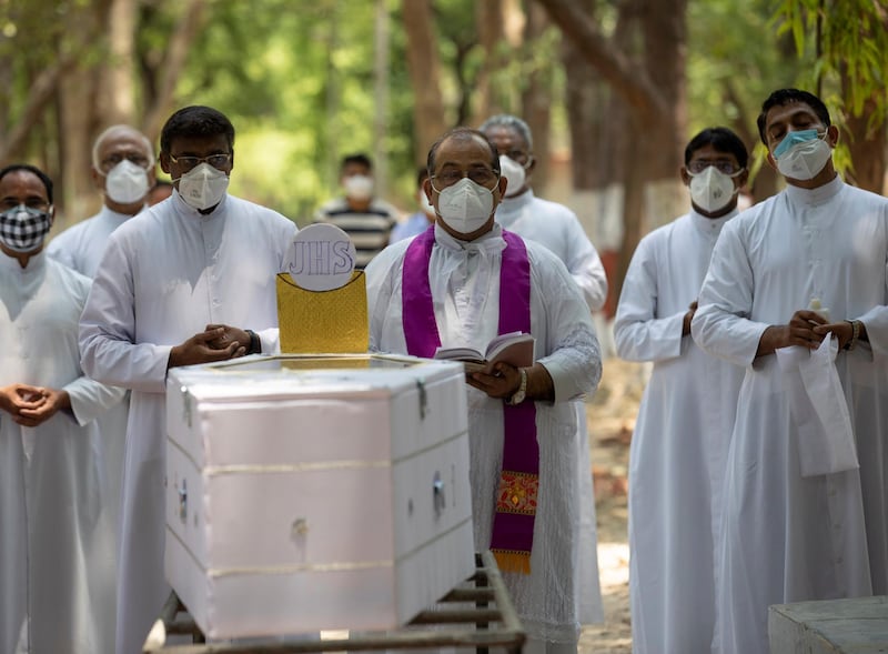 Christian priests at a cemetery in Prayagraj offer prayers next to the coffin of Father Rolfie D'Souza, who died of Covid-19. AP Photo