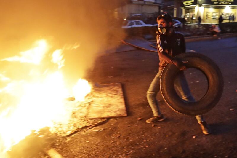A protester throws a tyre onto a burning barricade during ongoing demonstrations in Beirut. AFP