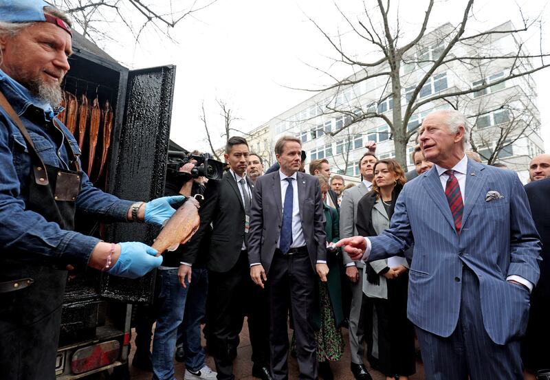 King Charles speaks with a market trader offering smoked herring. PA