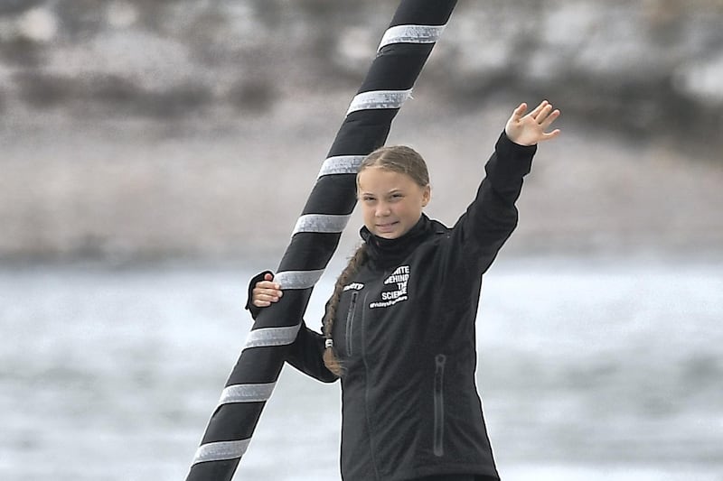 Swedish climate activist Greta Thunberg waves from aboard the Malizia II IMOCA class sailing yacht off the coast of Plymouth, southwest England, on August 14, 2019, as she starts her journey across the Atlantic to New York where she will attend the UN Climate Action Summit next month. - A year after her school strike made her a figurehead for climate activists, Greta Thunberg believes her uncompromising message about global warming is getting through -- even if action remains thin on the ground. The 16-year-old Swede, who sets sail for New York this week to take her message to the United States, has been a target for abuse but sees that as proof she is having an effect. (Photo by Ben STANSALL / AFP)