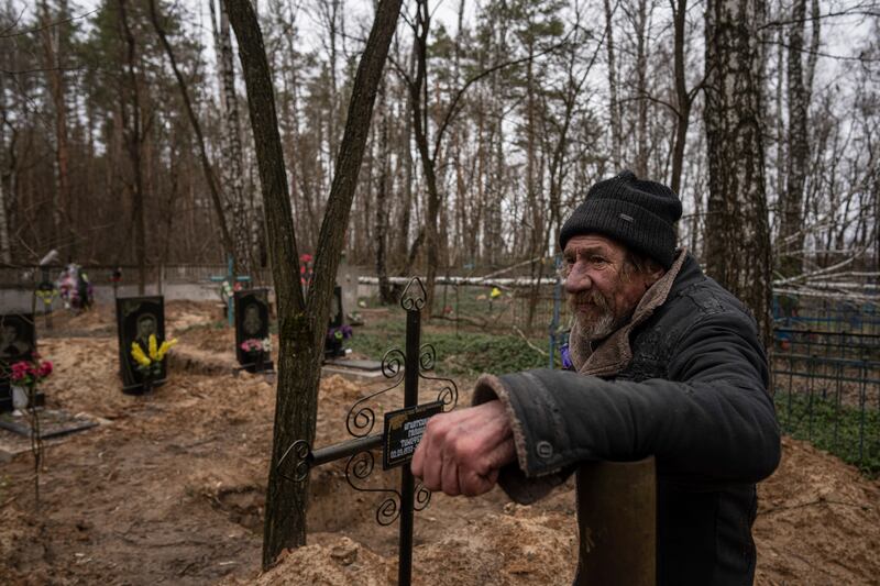 Vasyl Cherepenko stands next to a mass grave at a cemetery in Yahidne, near Dnipro, Ukraine. AP