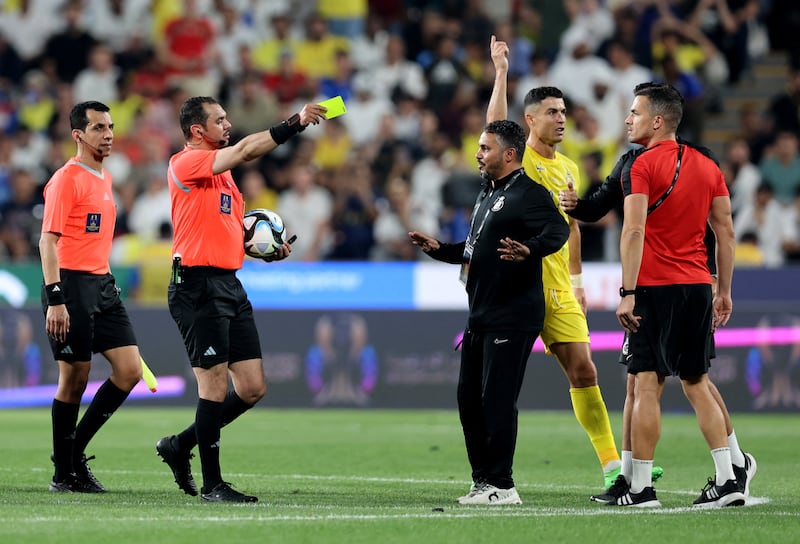 Al Nassr's Cristiano Ronaldo is shown a yellow card by referee Mohammed Al Hoaish as they walk off at half time. Reuters