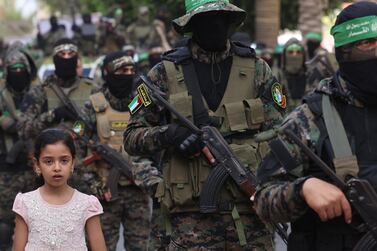 A girl looks on as members of Al-Qassam brigades, the armed wing of the Palestinian Hamas group, march in Gaza City on May 22, 2021, in commemoration of Senior Hamas Commander Bassem Issa who was killed along others in Israeli airstrikes. / AFP / Emmanuel DUNAND