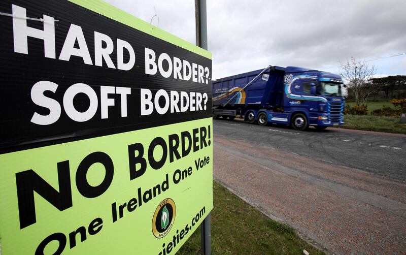 A lorry passes a poster by calling for "No Border" between Ireland and Northern Ireland, in a post Brexit United the anti-brexit campaign group "Border communities against Brexit" in Jonesborough, Northern Ireland on March 25, 2019, as it crosses the border between Ireland and Northern Ireland.  Keeping the Irish border free-flowing has proved to be the toughest issue to resolve in negotiating Britain's exit from the European Union. The Brexit deal between London and Brussels -- overwhelmingly rejected last week by British MPs -- contains a so-called backstop provision ensuring that if all else fails, the border will remain open. / AFP / PAUL FAITH
