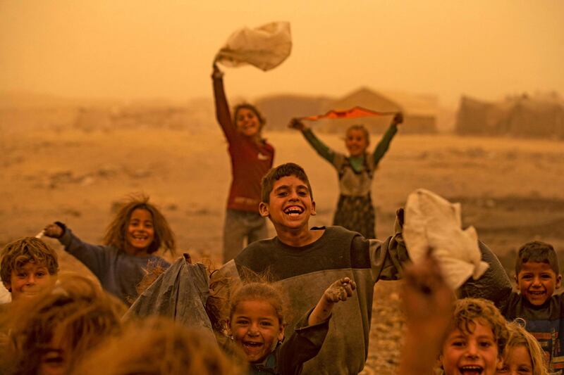 Children play during a sandstorm at the Sahlah al-Banat camp for displaced people in the Raqa countryside, north Syria. AFP