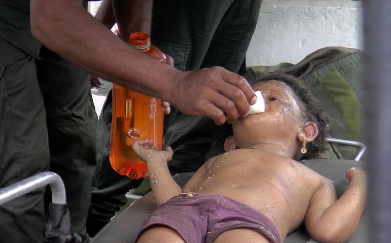 A Sri Lankan soldier cleans the face of a girl after she was found at the site of an explosion. Reuters