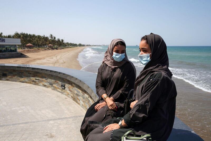 Omanis, wearing protective face masks, sit on the corniche in the capital Muscat, during the coronavirus pandemic.   AFP