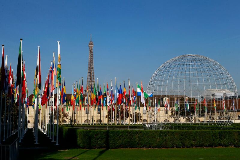 FILE - In this Tuesday Oct. 31, 2017 file picture, the Eiffel Tower, country flags and the Dome are seen from the garden of the United Nations Educational, Scientific and Cultural Organisation (UNESCO) headquarters building during the 39th session of the General Conference at the UNESCO headquarters in Paris, France. The United States and Israel have quit the U.N.â€™s educational, scientific and cultural agency, arguing the organization fosters anti-Israel bias.  (AP Photo/Francois Mori, File)