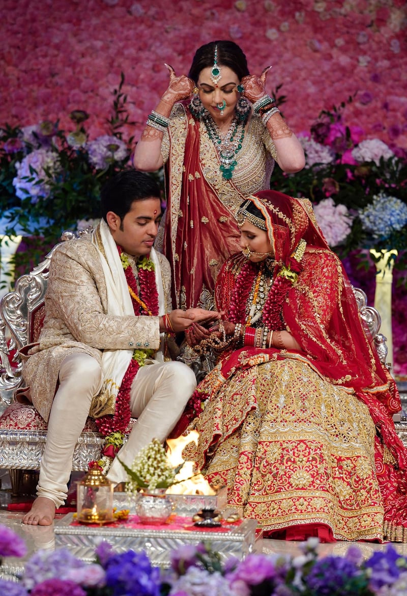 Nita Ambani, center, wife of Reliance Industries Chairman Mukesh Ambani, gestures as her son Akash Ambani, left, and daughter-in-law Shloka Mehta perform a ritual at their wedding ceremony in Mumbai, India. Photo: Reliance Industries Limited Photo via AP