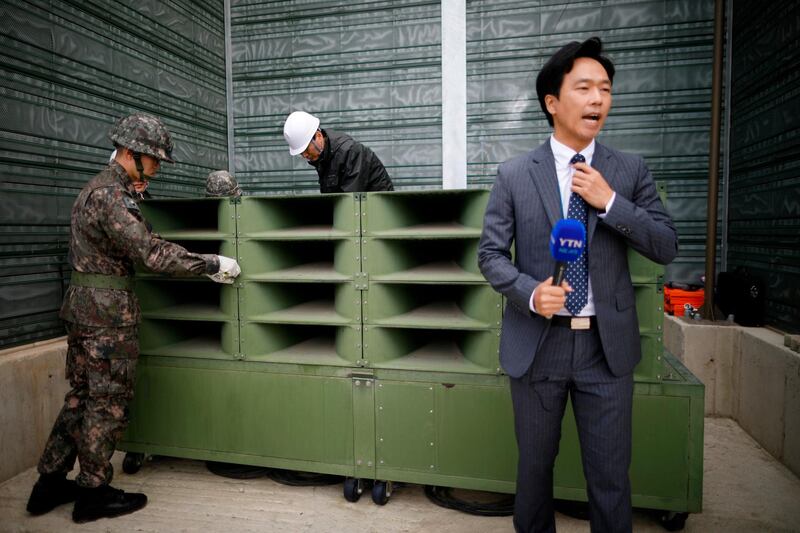 A reporter prepares a news bulletin as South Korean soldiers dismantle loudspeakers for propaganda broadcasts to North Korea in the demilitarized zone separating the two Koreas in Paju, South Korea. Kim Hong-Ji / AP Photo