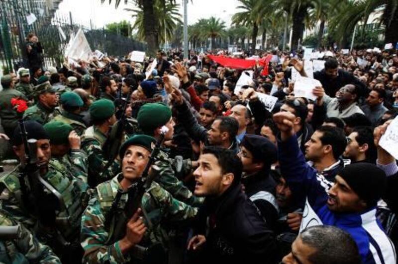 Soldiers hold back a crowd of protesters in front of the headquarters of the Constitutional Democratic Rally (RCD) party of ousted president Zine al-Abidine Ben Ali during a demonstration in downtown Tunis, January 20, 2011. Tunisian police fired shots into the air on Thursday to try to disperse hundreds of protesters demanding that ministers associated with the rule of ousted president Zine al-Abidine Ben Ali leave the government. The protesters, who had gathered outside the central Tunis headquarters of the RCD, Tunisia's ruling party for several decades, refused to move back when the police fired shots from behind a metal fence. REUTERS/ Finbarr O'Reilly (TUNISIA - Tags: CIVIL UNREST POLITICS)