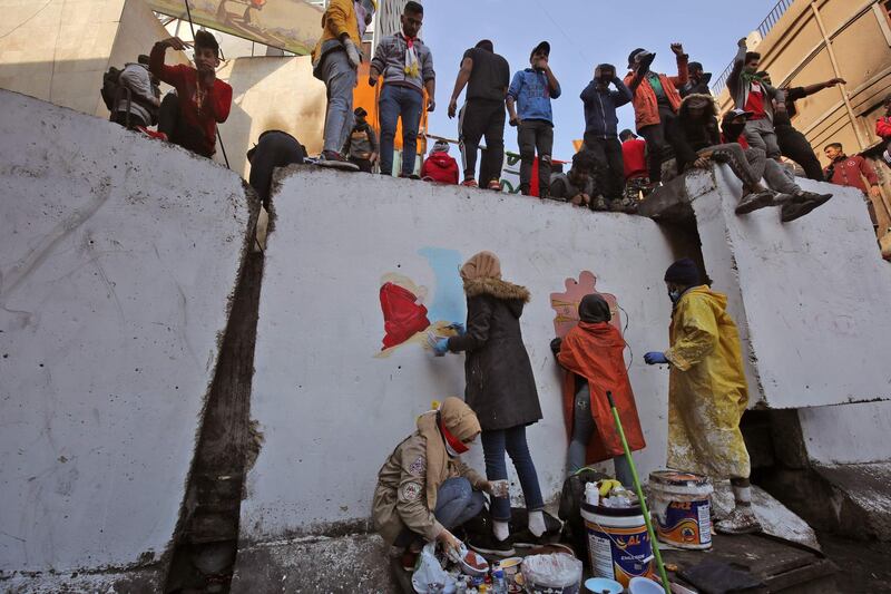 Iraqi protesters paint on a concrete barrier.  AFP