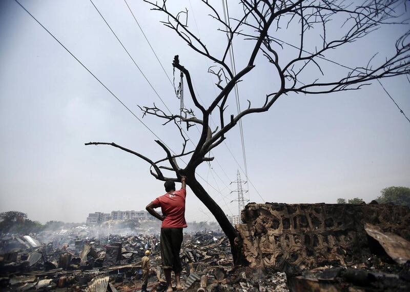 A resident stands next to the debris of huts after a fire broke out in a slum area in New Delhi. Hundreds of huts were gutted in the fire but no casualties were reported and the cause of the fire was unknown, slum dwellers said on Friday.  Anindito Mukherjee / Reuters / April 25, 2014