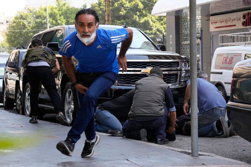 A man runs to take cover as supporters of a Shiite group allied with Hezbollah help injured men.  AP