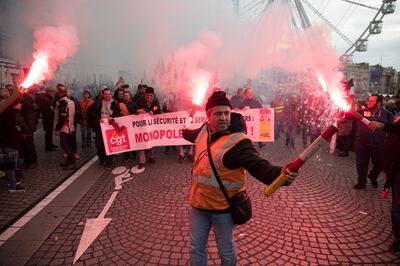 A railworker holds a flare during a mass stirke in the Old Port of Marseille, southern France, Wednesday, Dec. 5, 2019. Workers across the public sector fear President Emmanuel Macron's reform will force them to work longer and shrink their pensions. AP Photo/Daniel Cole)