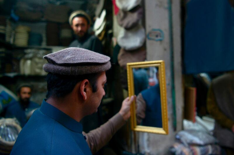 Trying on a Chitrali woolen cap, popular among locals, people particularly during winter, at a bazaar in Peshawar on December 3. AFP