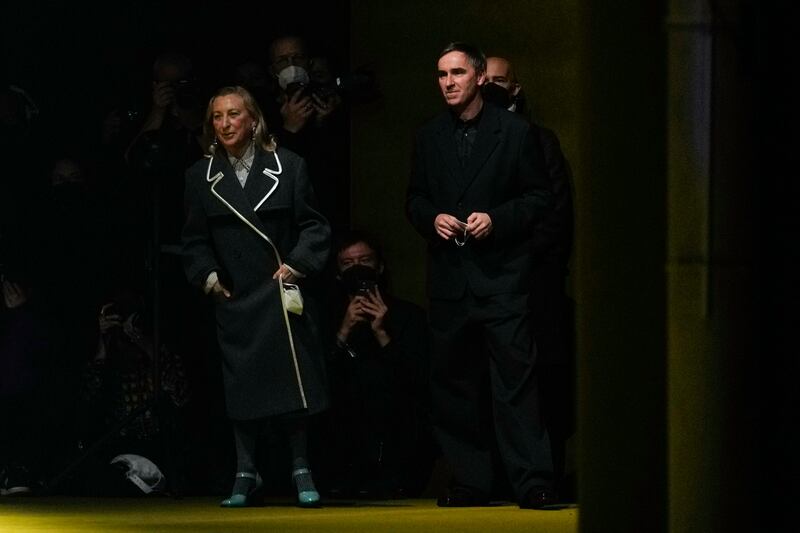 Italian designer Miuccia Prada, left, flanked by co-designer Raf Simons, accepts applause at the end of her Prada Men's autumn/winter 2022/23 show. AP