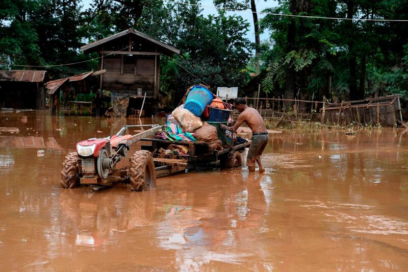 A man loads belongings on a tractor near his flooded home in Sanamxai, Attapeu province. AFP