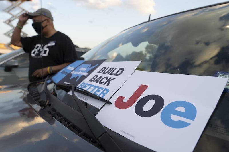 A Joe Biden supporter places signs on his car during a drive-in DNC watch event in Houston, Texas. AFP