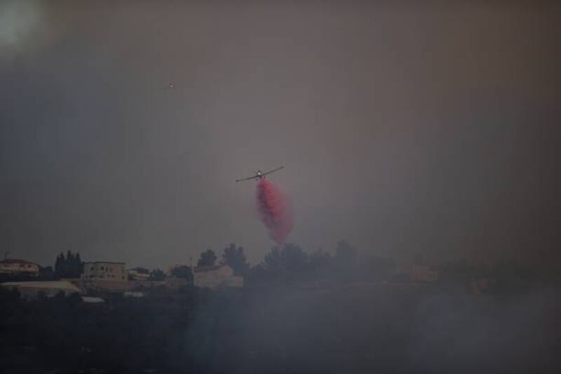 A plane dumps fire-retardant chemicals on forest fire in Beit Meir, in West Jerusalem, on August 15. Getty