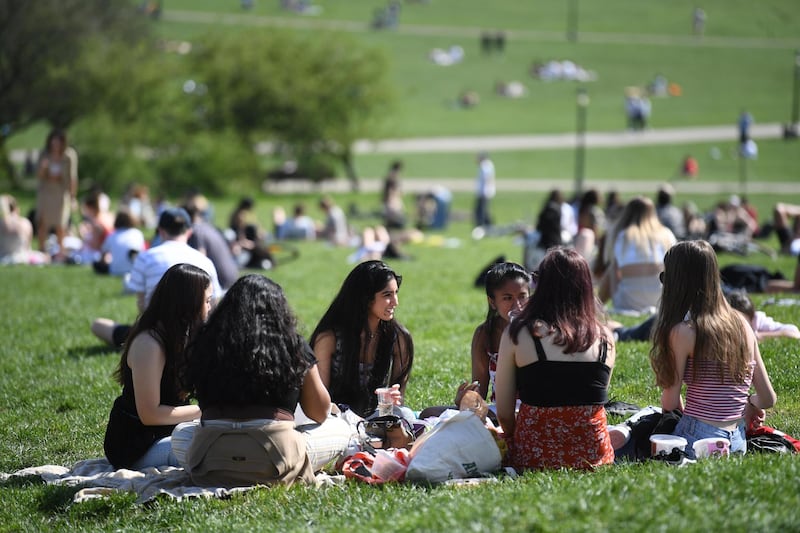 Groups sit in the sunshine at Primrose Hill, London. EPA