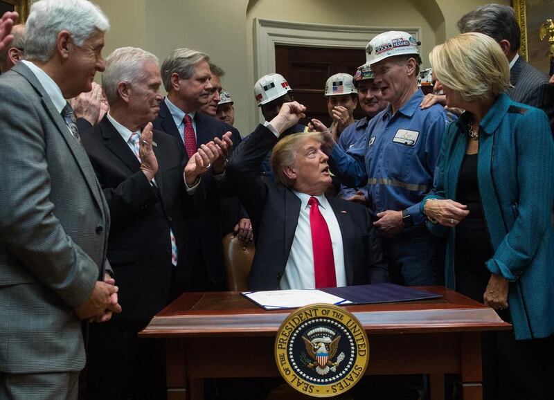 US president Donald Trump hands coal miners the pen he used to sign a bill eliminating regulations on the mining industry in the Roosevelt Room at the White House in Washington, DC. The new law nullifies a rule from protecting streams. Nicholas Kamm / Agence France-Presse / February 16, 2017