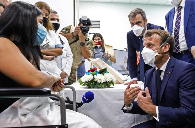 French President Emmanuel Macron speaks to a patient during a visit to Rafik Hariri University Hospital in Beirut with French Health Minister Olivier Veran, right, on September 1, 2020. AFP