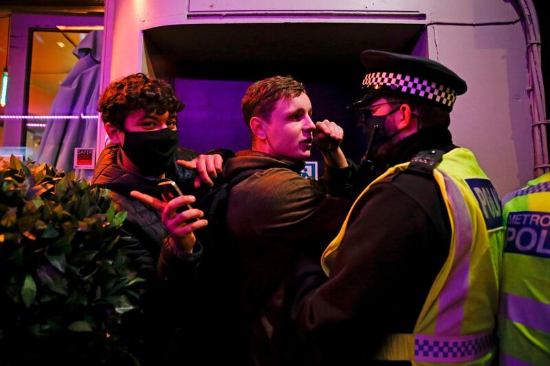 A man reacts during scuffles with police officers trying to disperse people prior to lockdown in the soho area of central London. AFP