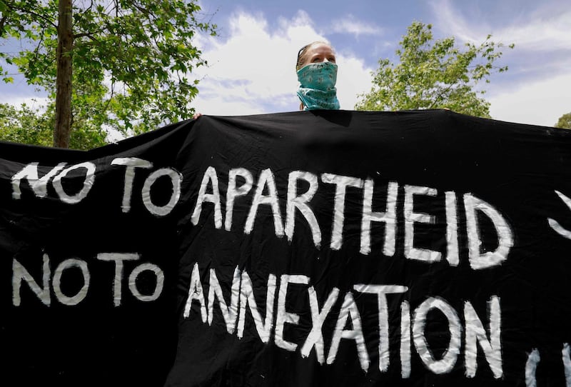 TOPSHOT - An Israeli activist holds a banner during a protest against the US peace plan for the Middle East, in front of the US ambassador's residence in Jerusalem, on May 15, 2020, as Palestinians commemorate the 72nd anniversary of the 1948 Nakba or "catastroph"  which left hundreds of thousands of Palestinians displaced by the war accompanying the birth of Israel. The US plan, rejected by the Palestinians, gives the green light from Washington for Israel to annex Jewish settlements and other territory in the occupied West Bank.  / AFP / Emmanuel DUNAND
