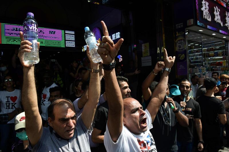 Members of the South Asian community hand out bottles of water to people taking part in a pro-democracy march outside Chungking Mansions, Hong Kong. AFP
