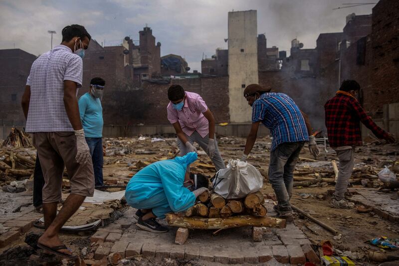 Siddiqui photographs Pranav Mishra, 19, as he kneels towards the body of his mother Mamta Mishra, 45, who died from coronavirus, in New Delhi, India. Reuters