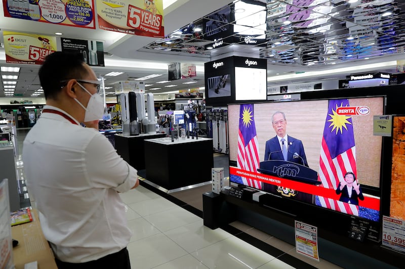 A man in Kuala Lumpur, Malaysia, watches a live broadcast of Malaysian Prime Minister Muhyiddin Yassin speak on Monday. AP