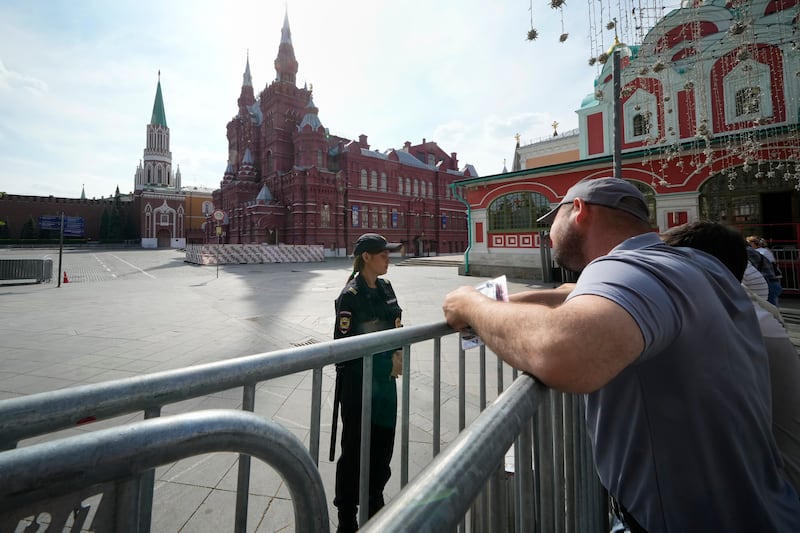 People speak with a police officer at the Red Square, in Moscow on June 25. Troops deployed in Moscow the previous day to protect the capital from Wagner mercenaries have withdrawn from the capital, and people swarmed the streets and flocked to cafes. Traffic returned to normal and roadblocks and checkpoints were removed. AP
