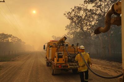 TOPSHOT - Firefighters refill their water from a water tanker in Pacific Drive in Deepwater National Park area of Queensland on November 28, 2018.  Thousands of people were being evacuated from their homes in northeast Australia as bushfires raged across Queensland state amid a scorching heatwave.
 / AFP / ROB GRIFFITH
