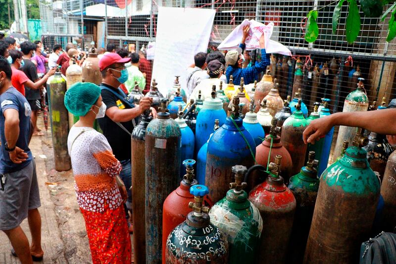 People wait to have oxygen tanks refilled outside the Naing oxygen factory in Yangon, Myanmar. AP