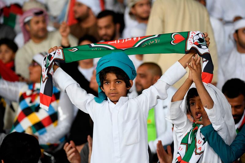 An Emirati boy carries a scarf before the preliminary round match between UAE and Bahrain in Abu Dhabi. AFP