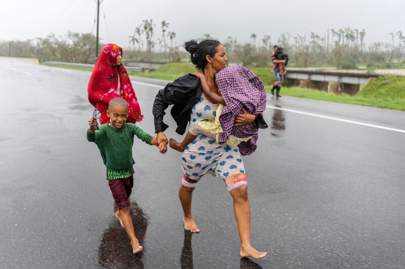 A family walks in the rain after Hurricane Ian hit Pinar del Rio, Cuba. AP