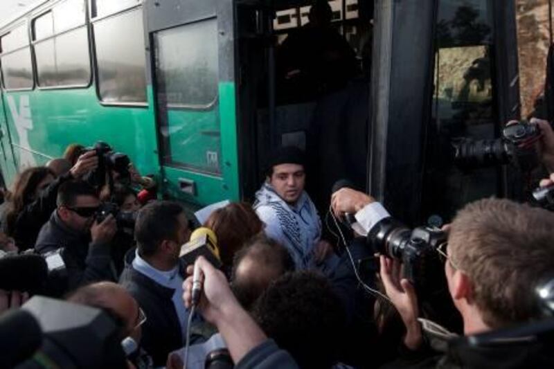 Reporters surround a Palestinian activist as he boards an Israeli bus outside the West Bank Jewish settlement of Migron, near Ramallah, on November 15, 2011. Palestinian "Freedom Riders" reenacted US civil rights movement's boarding of segregated buses in the American south by riding Israeli settler buses to Jerusalem. Several Israeli transportation companies operate dozens of lines that run through the occupied West Bank and east Jerusalem, many of them subsidized by the state. While it is not officially forbidden for Palestinians to use Israeli public transportation in the West Bank, these lines are effectively segregated, since many of them pass through Jewish-only settlements, to which Palestinian entry is prohibited by a military decree.    AFP PHOTO/AHMAD GHARABLI
 *** Local Caption ***  274044-01-08.jpg