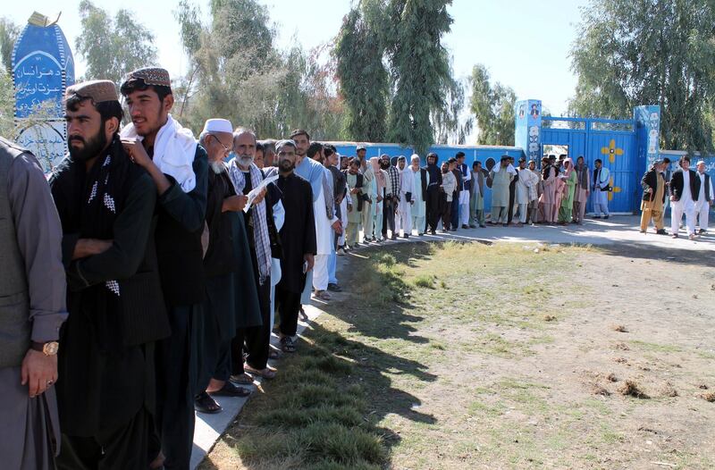 Afghan men line up to cast their votes, outside a polling station during the Parliamentary election in Helmand province, south of Afghanistan. AP