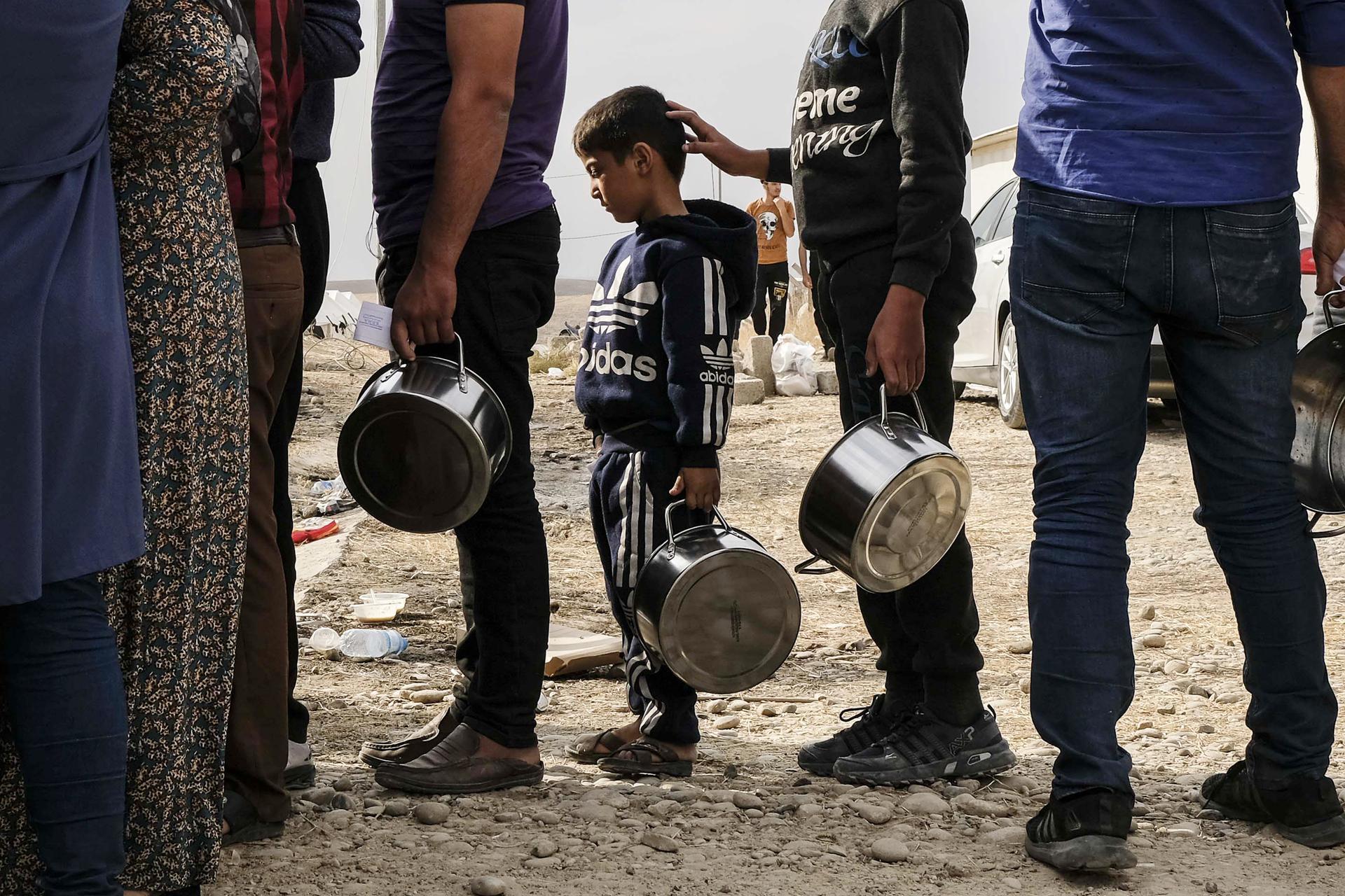DOHUK, IRAQ - OCTOBER 17: (EDITOR'S NOTE: Alternate crop of #1176332462 ) Syrian refugees fleeing the Turkish incursion in Northern Syria wait to receive water, bread and lentil soup as more than 200 arrive at the Bardarash IDP camp on October 17, 2019 in Dohuk, Iraq. More than 1000 refugees have arrived in Northern Iraq since the beginning of the conflict, with many saying they paid to be smuggled through the Syrian border. (Photo by Byron Smith/Getty Images) *** BESTPIX ***