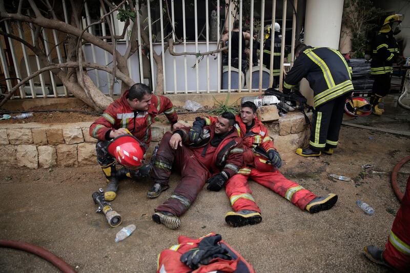 Lebanese firemen rest outside a building that was damaged in a wildfire in the town of Damour, about 15kmsouth of Beirut. AP Photo